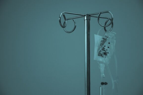 An IV bag on a stainless steel stand, illustrating clinic NAD+ drip pricing against at home programs