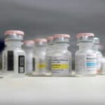 A 10 mL multi-dose ketamine hydrochloride vial on a clinic counter beside other injectable drug vials